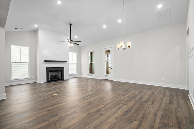 unfurnished living room featuring visible vents, dark wood-type flooring, ceiling fan with notable chandelier, a large fireplace, and lofted ceiling