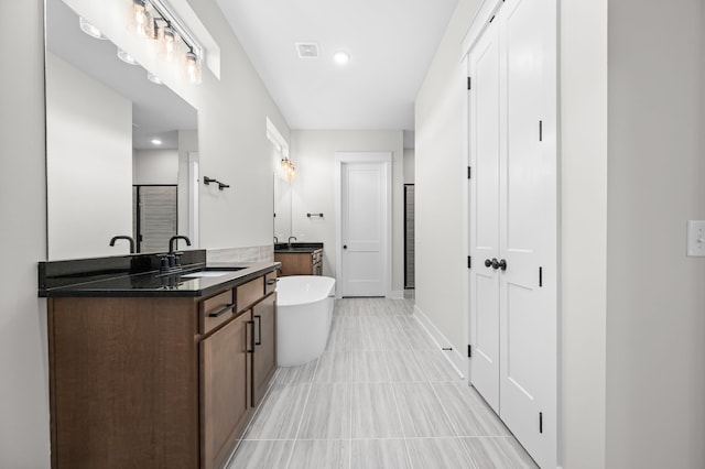 full bath with a stall shower, a freestanding bath, two vanities, and a sink