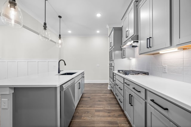 kitchen featuring gray cabinetry, a sink, under cabinet range hood, stainless steel appliances, and crown molding