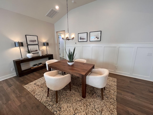 dining area featuring visible vents, lofted ceiling, an inviting chandelier, a decorative wall, and dark wood-style flooring