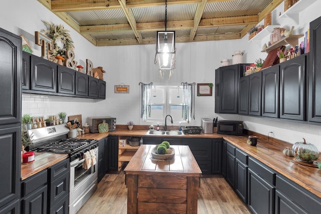 kitchen featuring pendant lighting, wood counters, sink, and high end stainless steel range