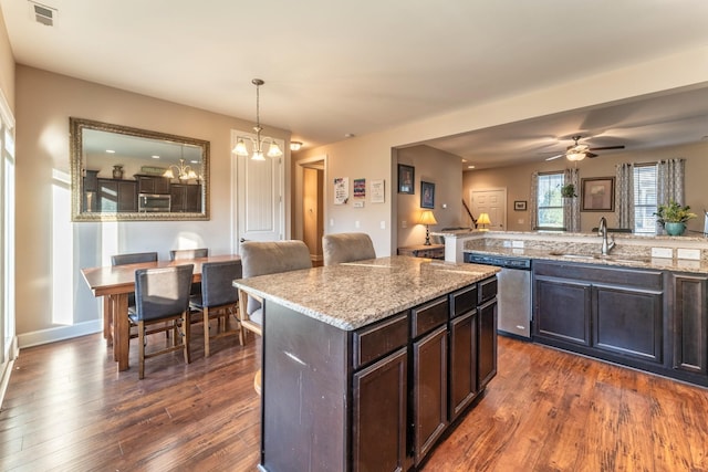 kitchen featuring appliances with stainless steel finishes, dark hardwood / wood-style flooring, ceiling fan with notable chandelier, sink, and hanging light fixtures