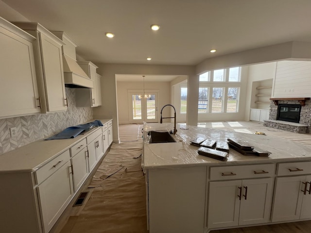 kitchen with cooktop, visible vents, custom range hood, a fireplace, and a sink