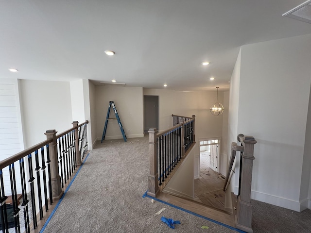 hall featuring baseboards, carpet flooring, an upstairs landing, a chandelier, and recessed lighting