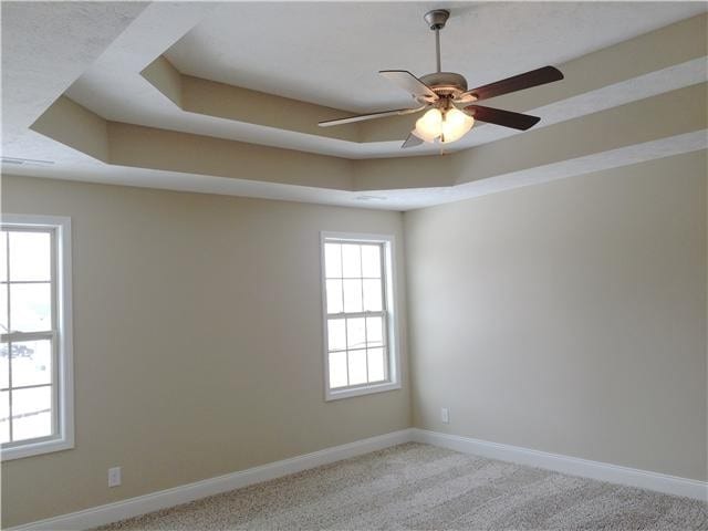 carpeted empty room featuring a tray ceiling and ceiling fan