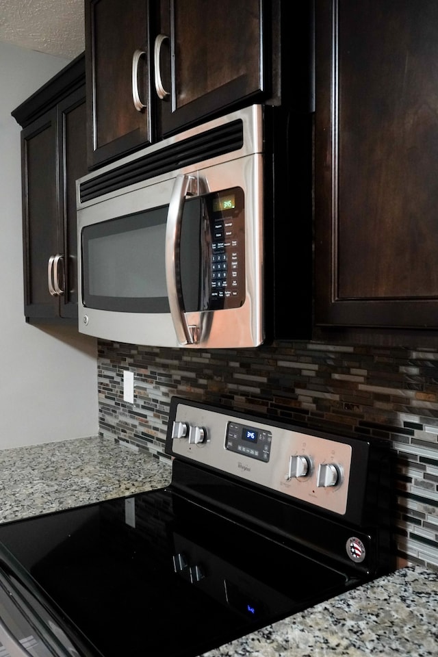 kitchen with dark brown cabinets, electric range oven, light stone counters, and tasteful backsplash