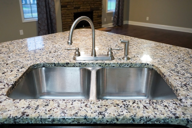 interior details featuring dark hardwood / wood-style floors, a fireplace, light stone counters, and sink