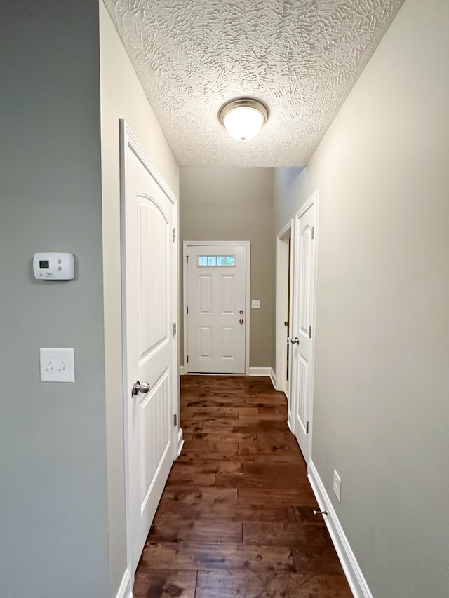 hall with dark hardwood / wood-style flooring and a textured ceiling