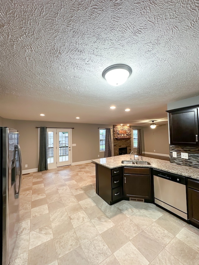 kitchen with light stone countertops, dark brown cabinets, a textured ceiling, and appliances with stainless steel finishes