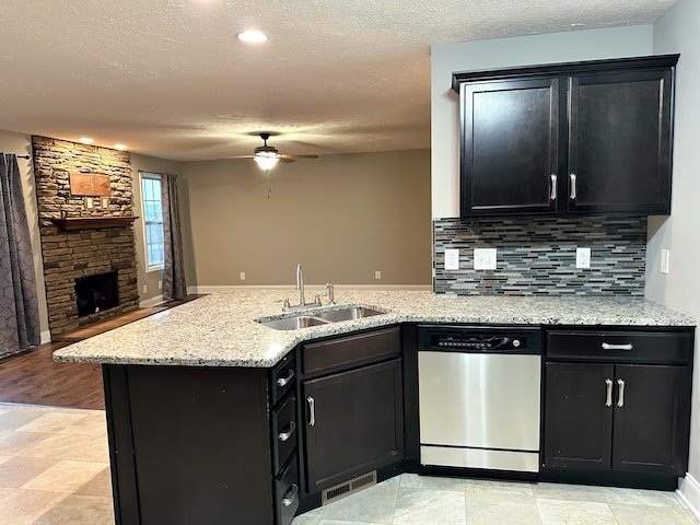 kitchen featuring a stone fireplace, sink, stainless steel dishwasher, ceiling fan, and kitchen peninsula