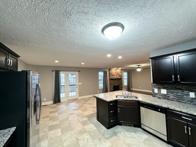 kitchen featuring appliances with stainless steel finishes, backsplash, light stone counters, and sink