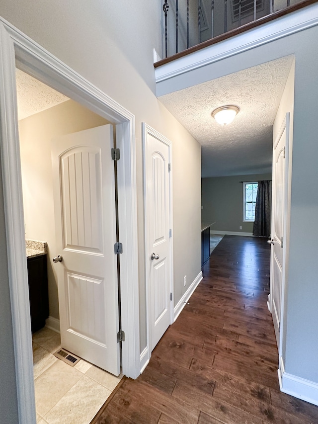 corridor with hardwood / wood-style floors and a textured ceiling