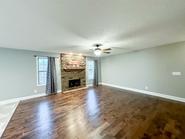 unfurnished living room featuring ceiling fan, a fireplace, dark wood-type flooring, and a textured ceiling