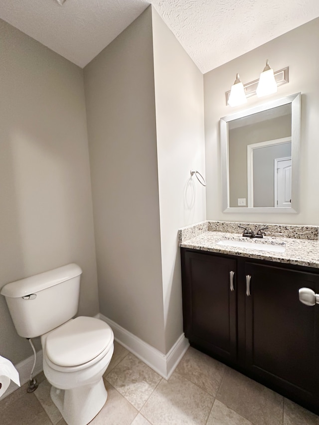 bathroom featuring tile patterned flooring, vanity, a textured ceiling, and toilet