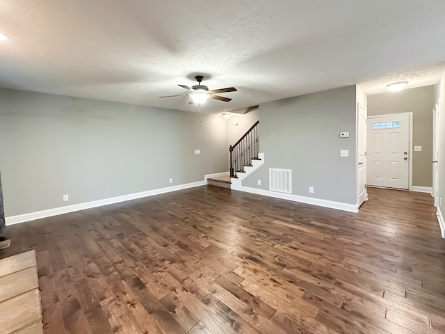 unfurnished living room with a textured ceiling, ceiling fan, and dark wood-type flooring