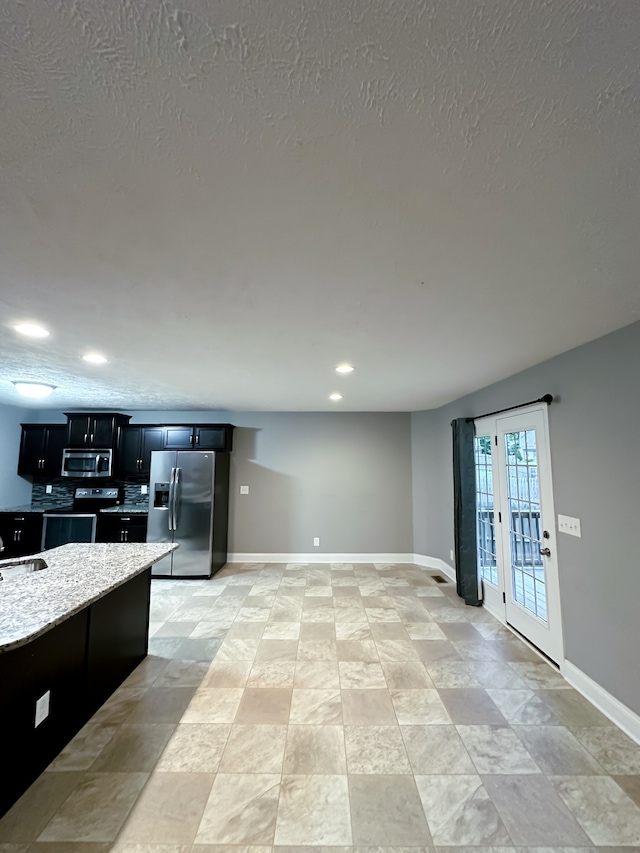 kitchen with light stone countertops, appliances with stainless steel finishes, a textured ceiling, and sink