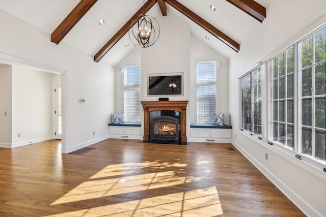 unfurnished living room with beam ceiling, hardwood / wood-style floors, high vaulted ceiling, and a chandelier