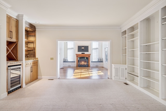 interior space with light colored carpet, wine cooler, and ornamental molding