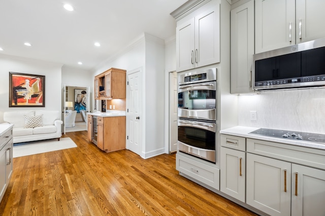 kitchen with decorative backsplash, appliances with stainless steel finishes, light wood-type flooring, crown molding, and gray cabinets