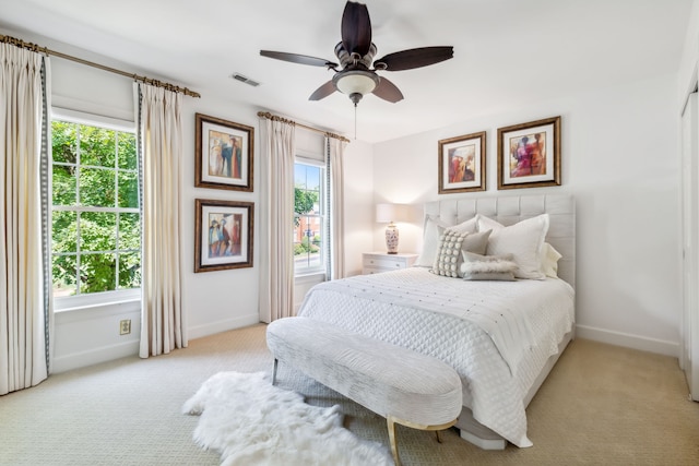 bedroom with light carpet, multiple windows, and ceiling fan