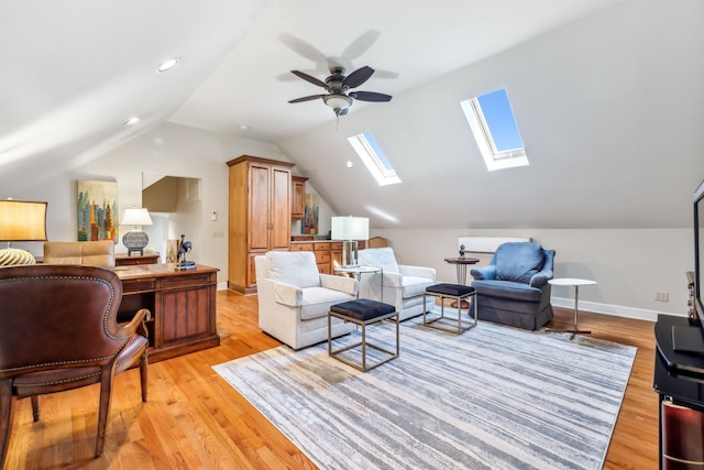 living room featuring ceiling fan, light hardwood / wood-style flooring, and vaulted ceiling with skylight