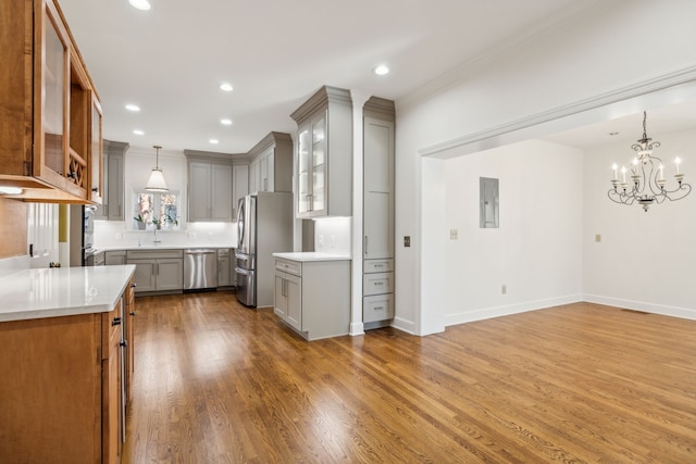 kitchen with wood-type flooring, stainless steel appliances, hanging light fixtures, and gray cabinetry