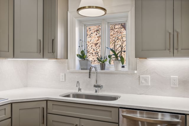 kitchen featuring stainless steel dishwasher, backsplash, gray cabinets, and sink