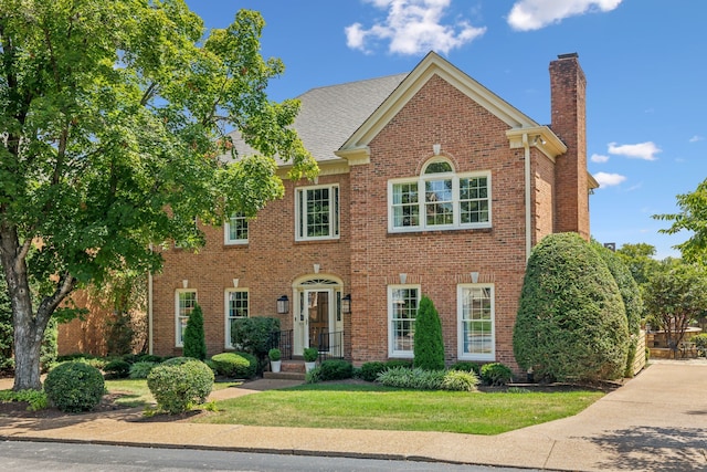 colonial-style house featuring a front yard