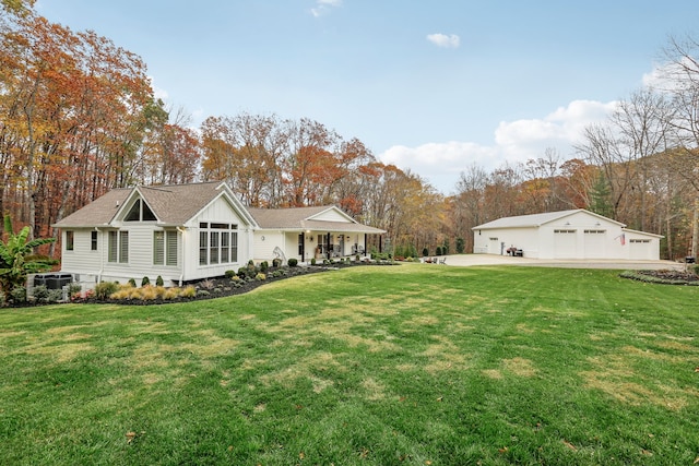 rear view of property with a lawn, a garage, an outbuilding, and covered porch