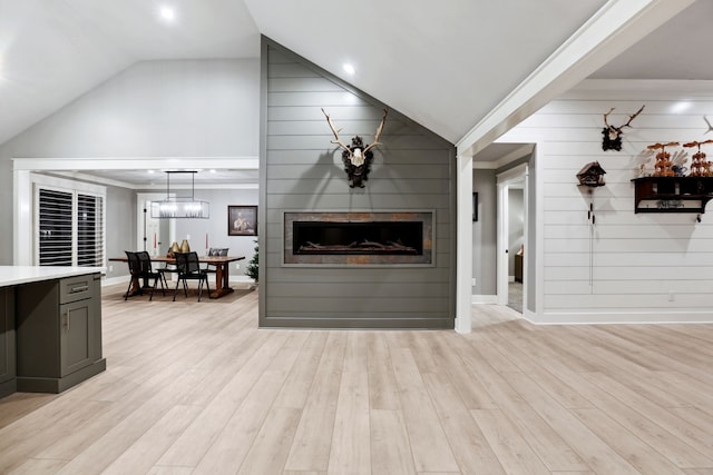 living room with a fireplace, light hardwood / wood-style floors, lofted ceiling, and wood walls