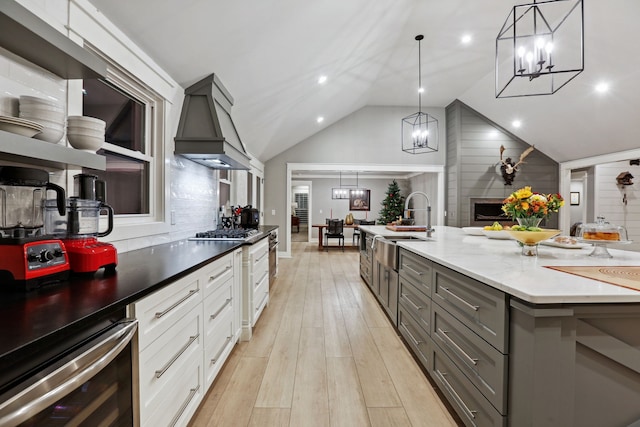 kitchen featuring white cabinets, decorative light fixtures, wood walls, and a fireplace