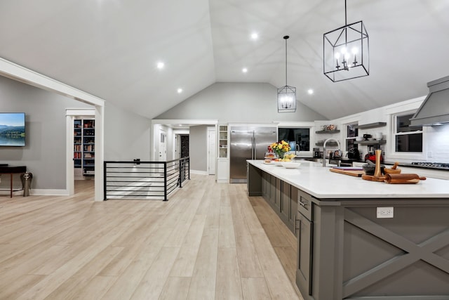 kitchen featuring gray cabinetry, a spacious island, light hardwood / wood-style flooring, built in refrigerator, and hanging light fixtures