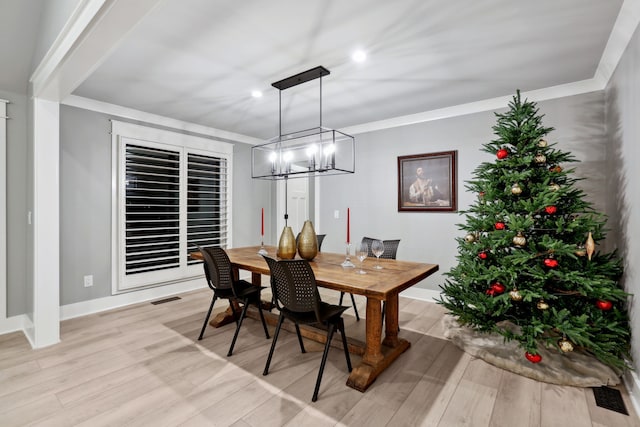 dining room featuring light hardwood / wood-style floors, crown molding, and an inviting chandelier