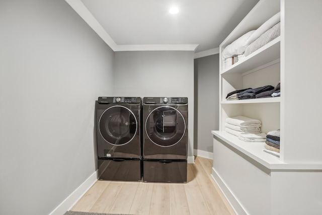 laundry area with washing machine and clothes dryer, light hardwood / wood-style floors, and ornamental molding