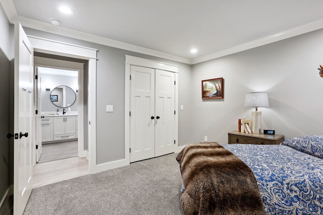 bedroom featuring light carpet, ensuite bath, a closet, and crown molding