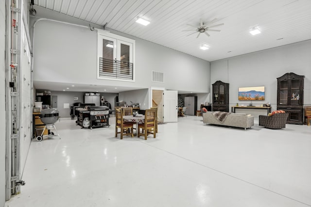 living room with ceiling fan, concrete flooring, and a high ceiling