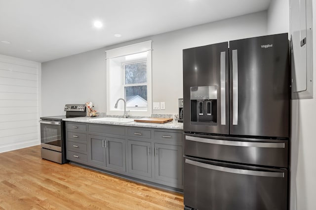 kitchen with appliances with stainless steel finishes, light hardwood / wood-style floors, gray cabinetry, and sink