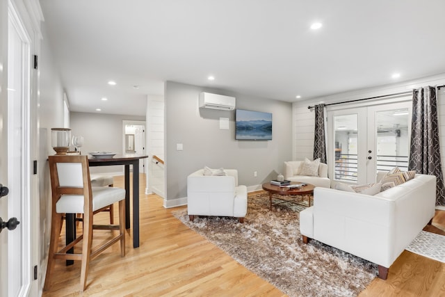 living room featuring a wall mounted air conditioner, light hardwood / wood-style floors, and french doors