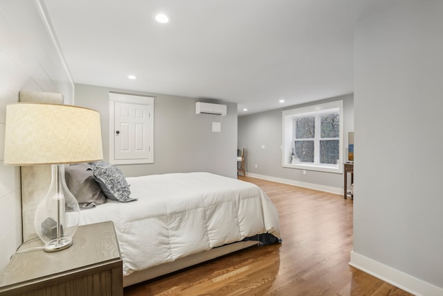 bedroom featuring a wall mounted AC and hardwood / wood-style flooring