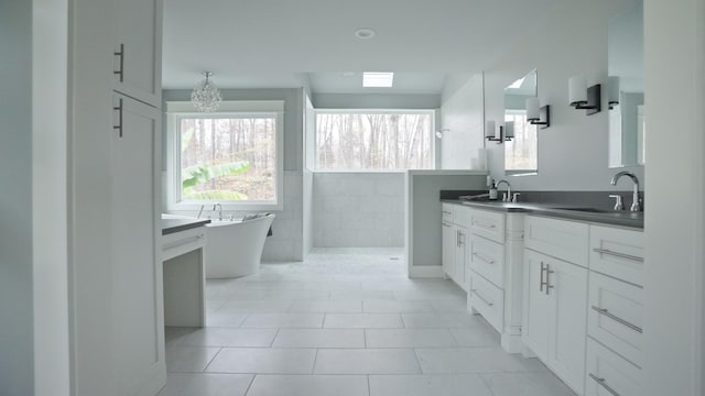 bathroom with a bathtub, vanity, tile patterned floors, tile walls, and a chandelier