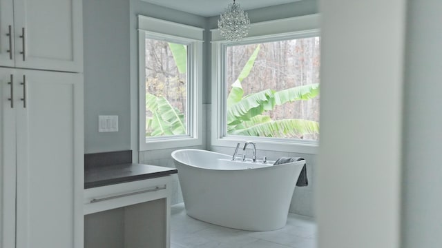 bathroom featuring a bath, vanity, a wealth of natural light, and a notable chandelier