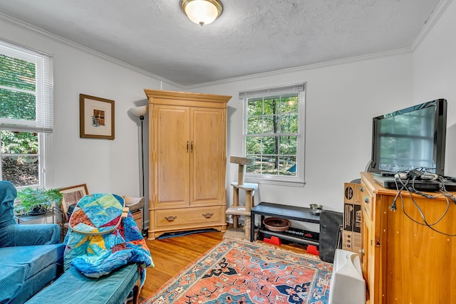 interior space with hardwood / wood-style floors, ornamental molding, and a textured ceiling