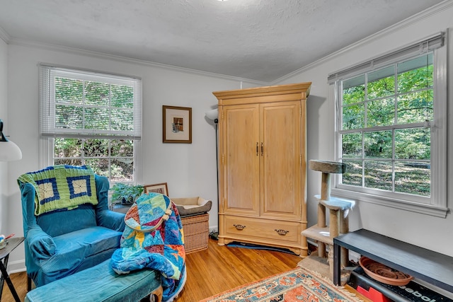 sitting room with wood-type flooring, crown molding, and a healthy amount of sunlight