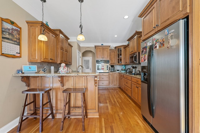 kitchen featuring kitchen peninsula, decorative backsplash, light wood-type flooring, stainless steel appliances, and decorative light fixtures