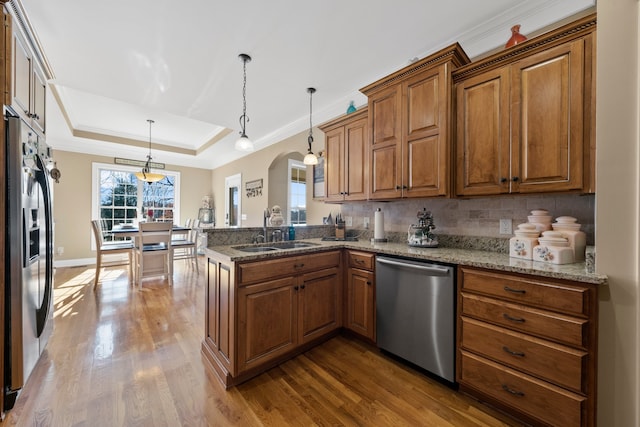 kitchen featuring sink, kitchen peninsula, stainless steel appliances, and hanging light fixtures