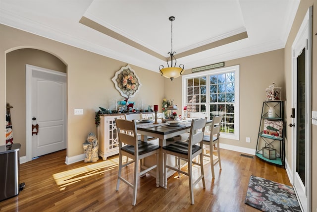 dining room featuring hardwood / wood-style floors, a raised ceiling, and crown molding