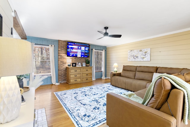 living room featuring ceiling fan, light hardwood / wood-style floors, and wood walls