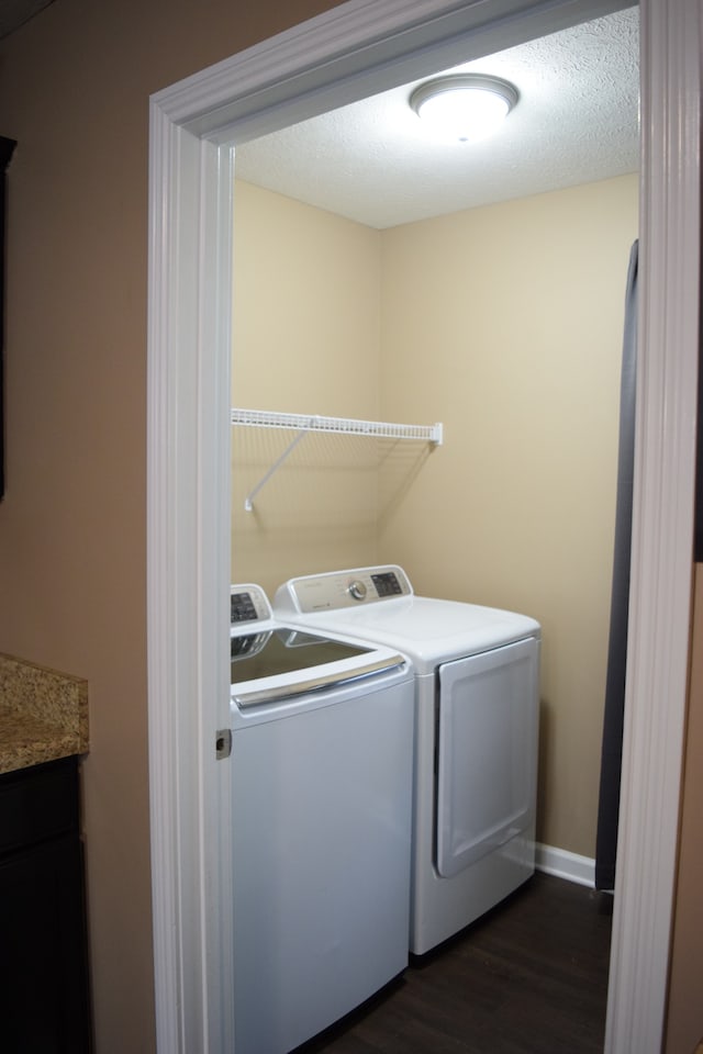 laundry room featuring a textured ceiling, dark wood-type flooring, and washing machine and clothes dryer