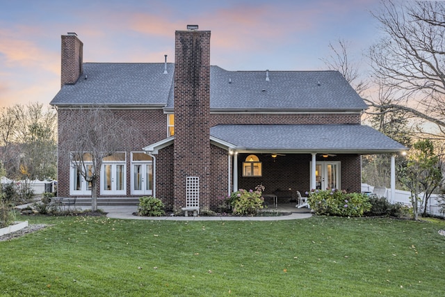 back house at dusk with a yard, ceiling fan, french doors, and a patio