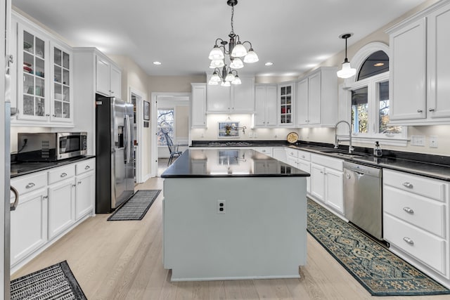 kitchen with appliances with stainless steel finishes, decorative light fixtures, a kitchen island, and sink